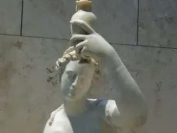 Seated marble female figure lifting one foot and holding a small vessel above her head.