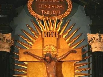 Gero Cross with a dark carved Christ figure on a golden crucifix, framed by Latin inscriptions and a sunburst backdrop.