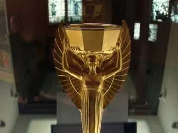 Jules Rimet Trophy replica with a winged female figure holding a cup aloft on a dark octagonal base.