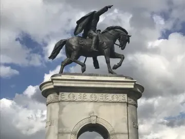 Sam Houston statue of a man on horseback atop a tall stone archway with people on the steps below.