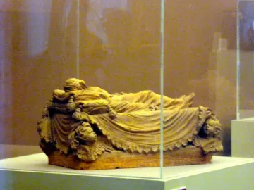 A bozzetto of the Veiled Christ showing a recumbent figure draped in finely folded fabric inside a glass display case.