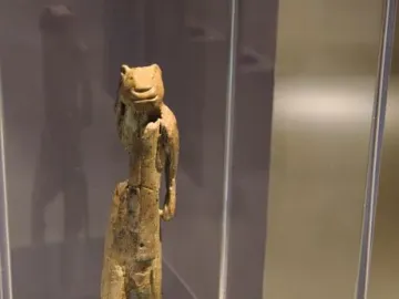 Lion-man figurine displayed in a glass case on a slender dark mount.