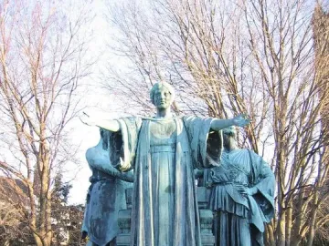 Alma Mater statue with a bronze female figure and two robed figures on a stone pedestal
