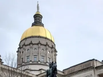 John Brown Gordon equestrian statue on a tall stone pedestal in front of a domed capitol building.