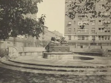 The Great God Pan fountain with a dark sculpture on a stone base in an urban park setting.