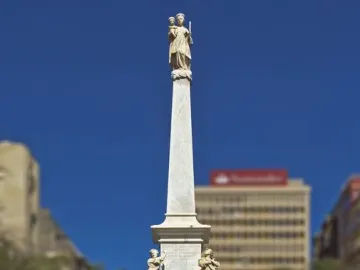 The Triumph of the Candelaria obelisk rises in an open plaza, with stone figures at the base and a white figure atop the monument.
