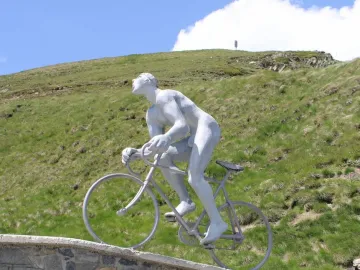 Géant du Tourmalet sculpture of a nude cyclist on a bicycle with three real cyclists standing below.