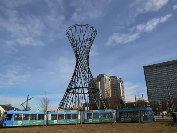 Mae West sculpture with a tram passing in front of it under a partly cloudy sky.
