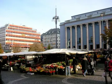 The Orpheus Fountain bronze statue is partially visible above market stalls in Stockholm.