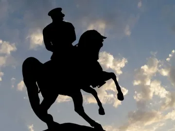 Silhouette of the Statue of Honor equestrian monument against a cloudy sky.