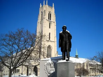 Taras Shevchenko Memorial statue on a snow-dusted pedestal with a church tower behind it.