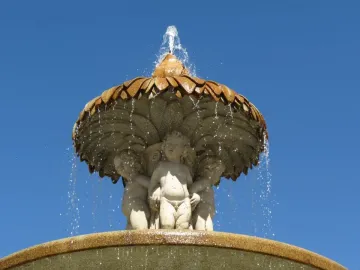 Fountain of the Artichoke with three cherubs supporting a leaf-covered stone canopy as water cascades over the edge.