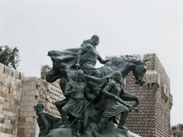 Saladin equestrian statue with armed figures in front of the Citadel walls in Damascus.