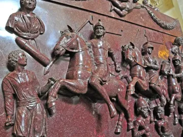 Relief carving on the Sarcophagus of Helena showing soldiers on horseback, standing figures, a bust, and winged figures with a garland.