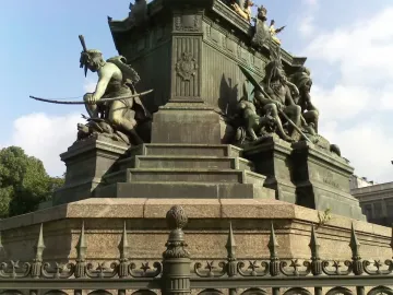 Ornate bronze and stone base of the Dom Pedro I Equestrian Statue with sculptural figures, including a crouching figure with a bow and a seated figure holding a spear.