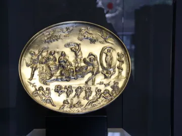 The Parabiago Plate, a gold-toned circular relief with a central chariot scene and surrounding mythological figures.