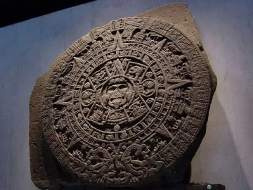 Aztec Sun Stone with intricate carved symbols and a central face surrounded by concentric rings.