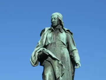 Vodnik Monument, a green-patinated statue of a man in historical clothing holding a rolled document on a white pedestal.