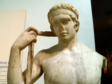 Farnese Diadumenos marble bust with a band on his head, holding a ribbon in his raised right hand.