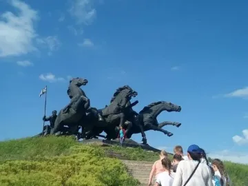 Legendary Tachanka monument with rearing horses and a flag-bearing figure on a green hill.