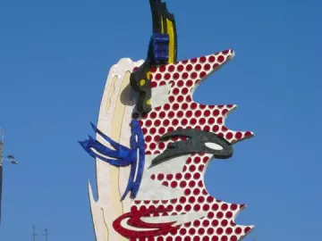 The Face of Barcelona sculpture with a red dotted pop-art pattern against a clear blue sky.