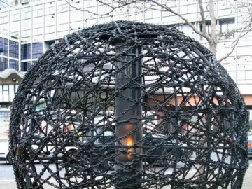 Universal Links on Human Rights sculpture with a dark spherical frame of chains and bars surrounding a central flame.