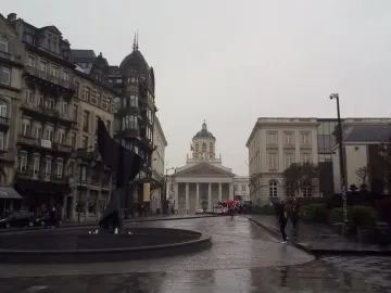 The Whirling Ear sculpture rises from a circular basin beside an urban street scene.