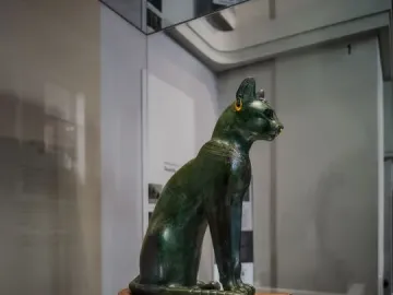 Gayer-Anderson Cat statue with a gold nose ring, earring, and decorated collar.