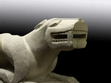 Leona de Baena stone sculpture shown in side profile, with an open mouth and extended paws.
