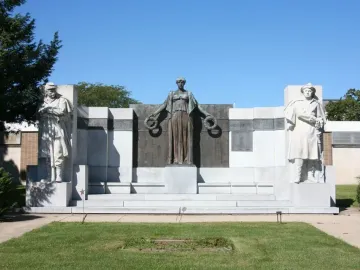 Soldiers\' Monument in Oregon, Illinois, featuring a bronze-toned draped female figure with wreaths flanked by two stone soldiers.