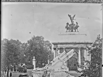Royal Artillery Memorial with a large howitzer on a tiered stone base, detailed reliefs, and draped figures, with ladders and workers nearby.