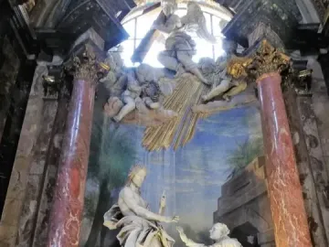 Noli Me Tangere sculpture showing a robed figure with an upraised hand facing a kneeling figure reaching out, set before a painted backdrop and framed by ornate columns.