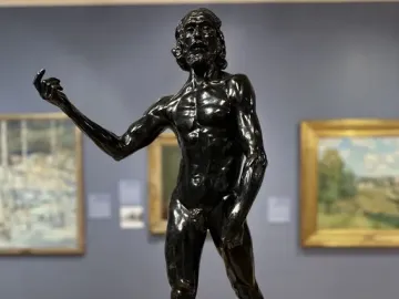 Saint John the Baptist by Auguste Rodin, a dark bronze sculpture of a gaunt male figure with an intense upward gaze and one arm extended.