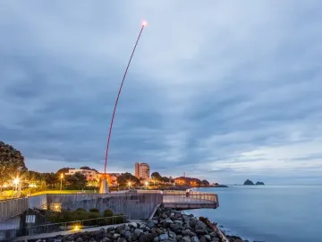 Wind Wand on a coastal promenade at dusk, lit at the tip against a cloudy evening sky.
