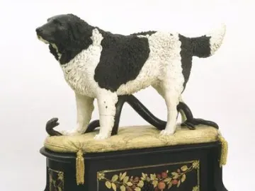 Bashaw sculpture of a black and white dog standing over a snake on a decorative pedestal.