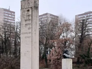 Karl Marx Monument showing a dark bust of a bearded man beside a tall stone stele with German text.