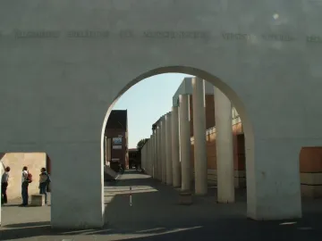 The Way of Human Rights concrete archway with engraved German text, framing a walkway lined with tall concrete pillars.