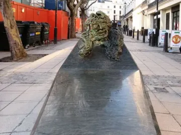 A Conversation with Oscar Wilde granite monument with a bronze bust holding a cigarette.