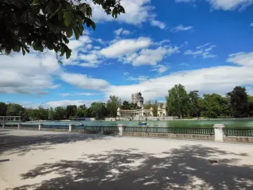 The Alfonso XII Monument rises across a lake, with an equestrian statue atop the monument and colonnades on the far shore.