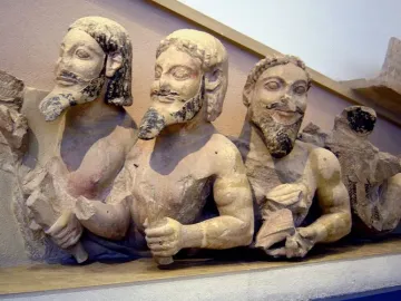 Trisomatos Typhon sculpture showing three male figures joined side by side, with dark traces of beard and hair and faint red pigment.
