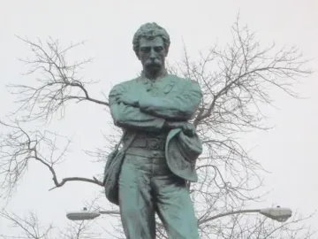 Appomattox bronze statue of a mustached man in military dress standing with arms crossed on a tiered stone pedestal.