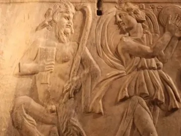 Relief on the Sarcophagus of the Triumph of Bacchus showing a satyr with a pan flute facing a dancing bacchante with a tambourine.