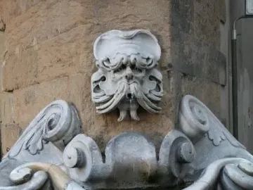 Fontana dello Sprone stone fountain with a carved bearded face spouting water into an ornate marble basin.