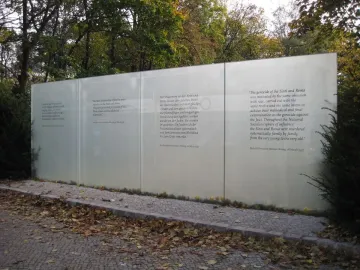 Translucent memorial panels with white multilingual text at the Memorial to the Murdered Sinti and Roma of Europe.