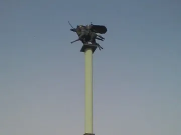 Polish Cavalry Monument on a tall pillar above a grassy mound, with dark horse and rider figures at the top.