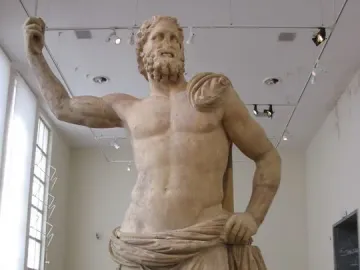 Poseidon of Melos marble statue of a bearded man with one arm raised, displayed in a museum gallery.