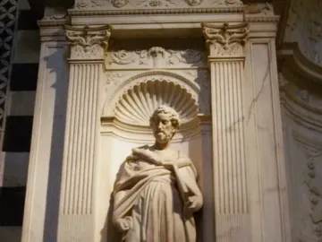 White marble statue of Saint Peter in the Piccolomini Altar at Siena Cathedral, shown in a twisting pose with a book held in his left arm.