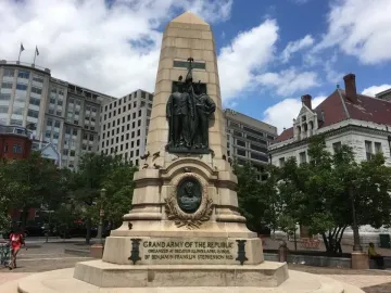 Stephenson Memorial, a tall stone obelisk with bronze figures, including two uniformed men holding a flag and a bust in a circular frame.