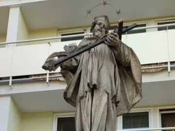 John of Nepomuk statue holding a crucifix on an ornate pedestal with a star-studded halo behind his head.