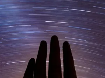 Mano del Desierto sculpture under arcing star trails in the night sky.